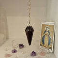 Wooden pendulum hanging on a chain against a blurred background