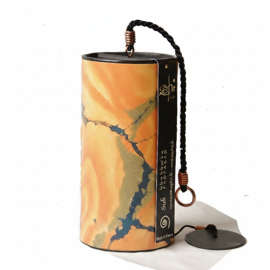 A cylindrical Sufi wind chime with a marbled orange, yellow, and green stone-like pattern, featuring a black hanging strap with copper-colored end caps and a black product label.