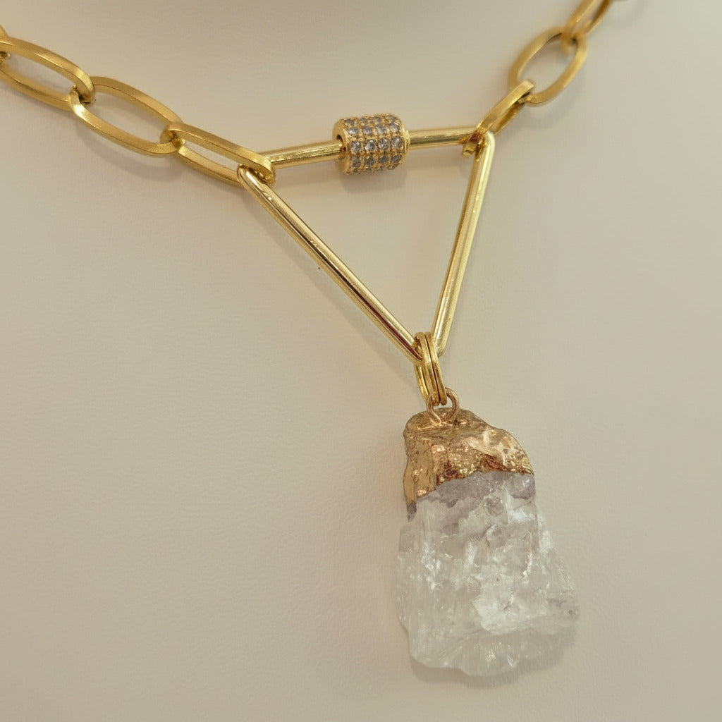 Gold necklace with natural rock quartz on a textured beige surface