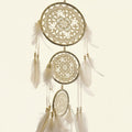 Decorative dreamcatcher with three circular designs and feathers on a beige background