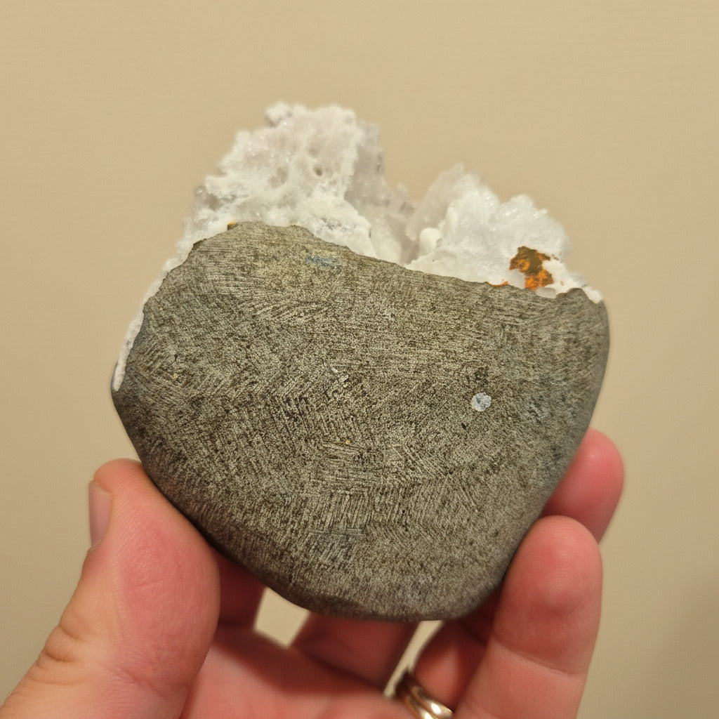 Hand holding a natural stone with a beige background