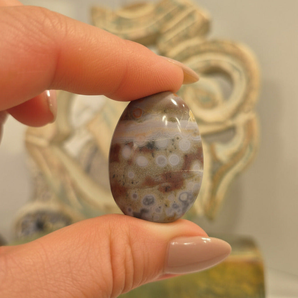 Hand holding a polka dot stone with a decorative background