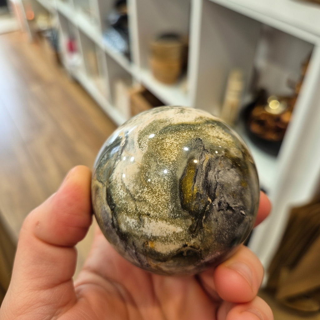 Hand holding a natural stone sphere with a blurred indoor background