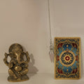 Close-up of a rose quartz pendulum with a clear pendant on a white background with ganesha and tarot