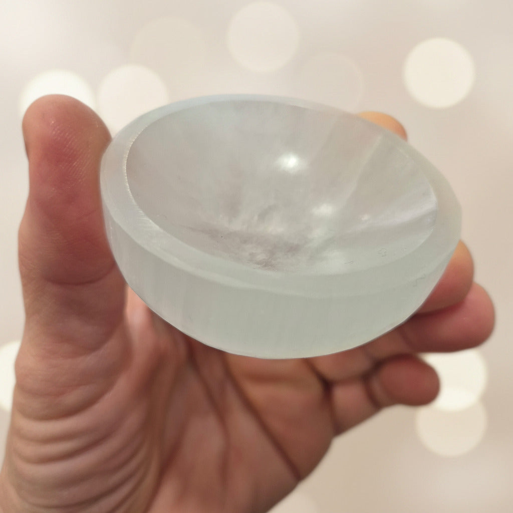 Hand holding a translucent white stone against a blurred background