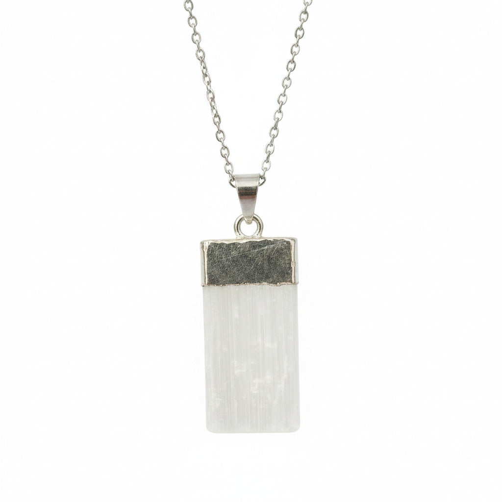 Crystal pendant with silver base held between fingers against a blurred background