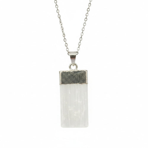 Crystal pendant with silver base held between fingers against a blurred background