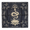 A square black bandana or scarf laid flat on a white surface featuring a cream-colored mystical design with a snake, sun, moon, lotus flower, geometric symbols, and decorative borders. The text 'OWN YOUR POWER' is printed on the right side.