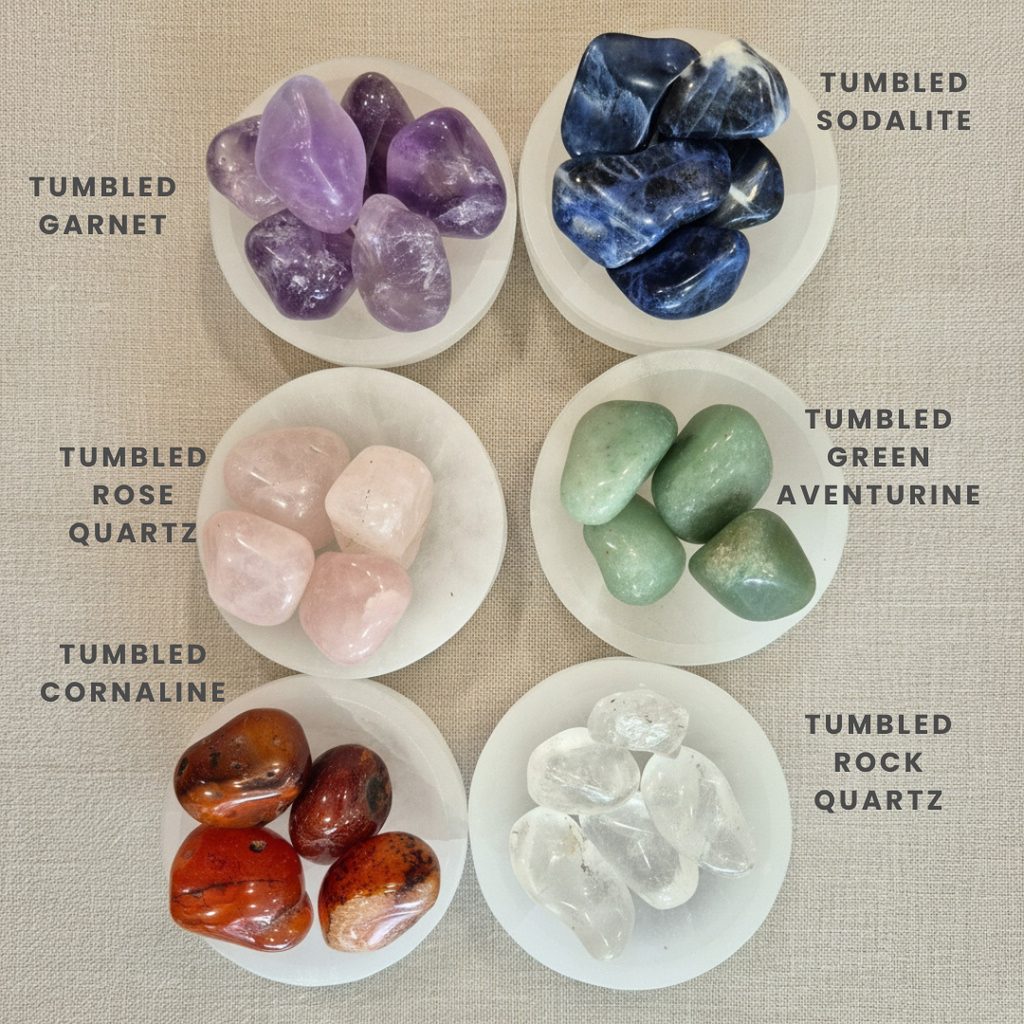 Collection of tumbled gemstones in various colors on a textured surface.