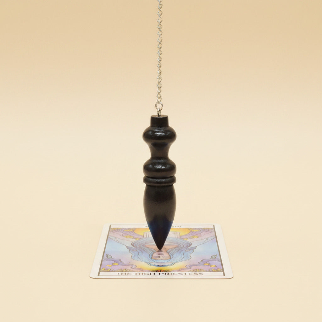 wooden pendulum with white surface over a tarot card